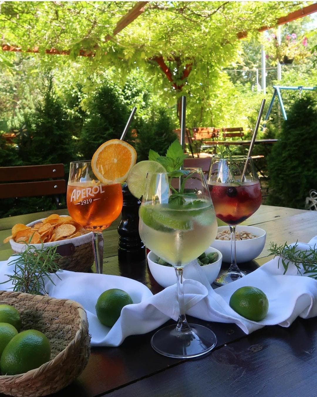 Aperol Spritz, Hugo und Lillet Wildberry auf einem Tisch unter der Pergola im Biergarten
