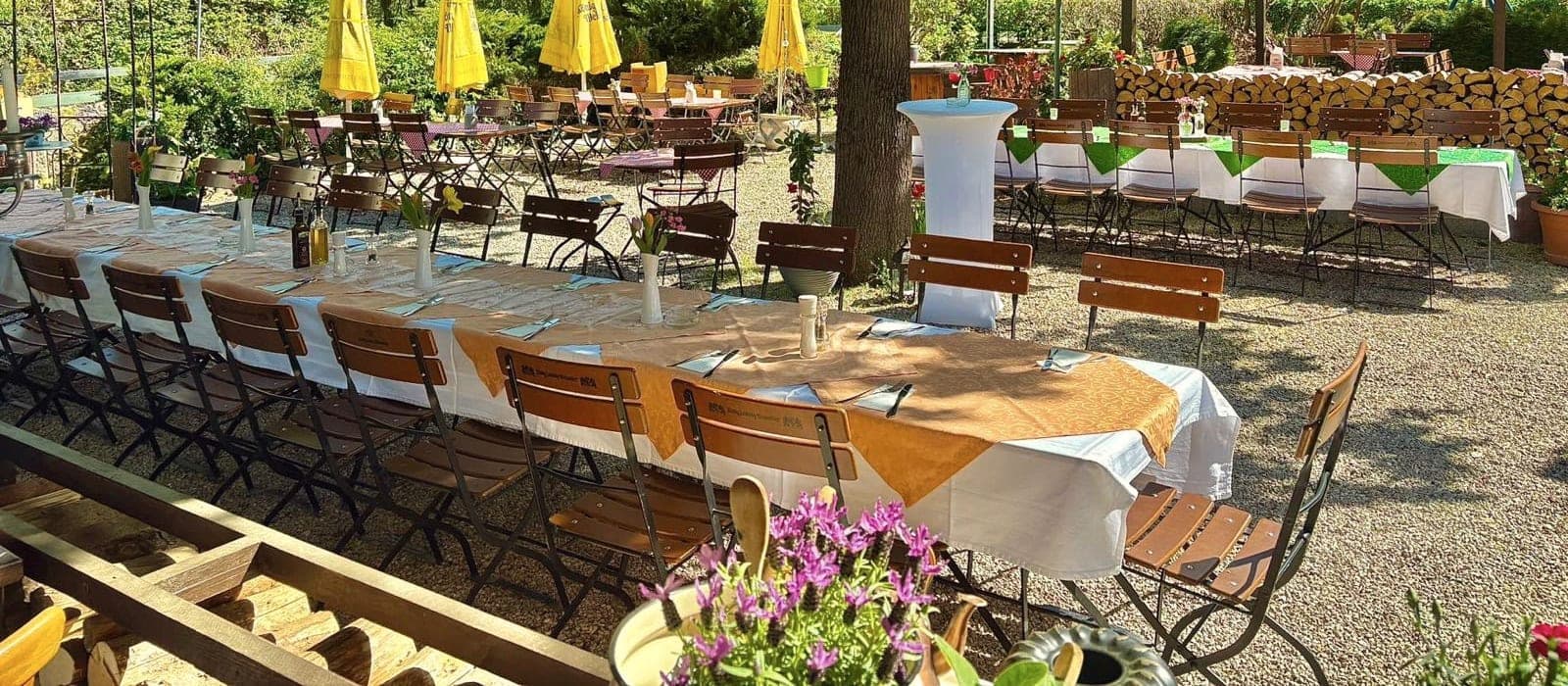 Eine lange, festlich gedeckte Tafel im sonnigen Biergarten