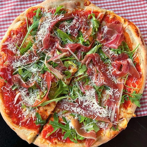 Pizza mit Parmaschinken, Rucola und Parmesan von oben