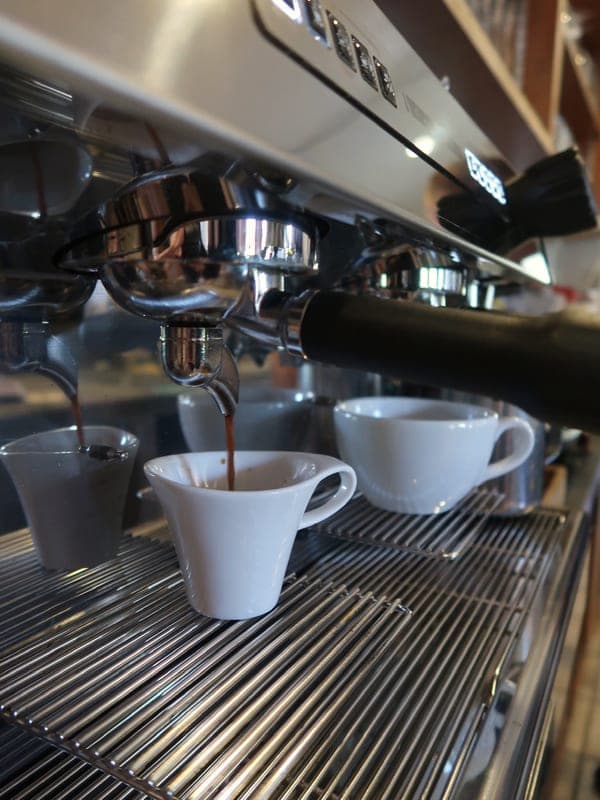 Espresso läuft aus dem Siebträger in eine weiße Tasse